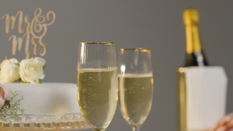 Wedding-Cake-With-Glasses-Of-Champagne-Against-Grey-Studio-Background-At-Wedding-Reception-3